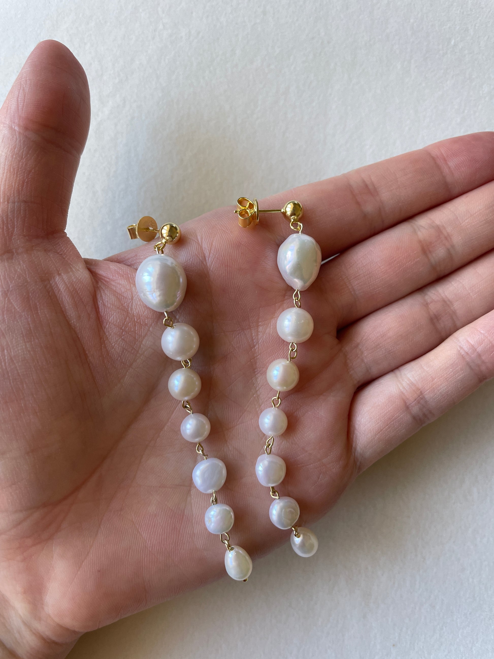 long_pearl_earrings_on_hand
